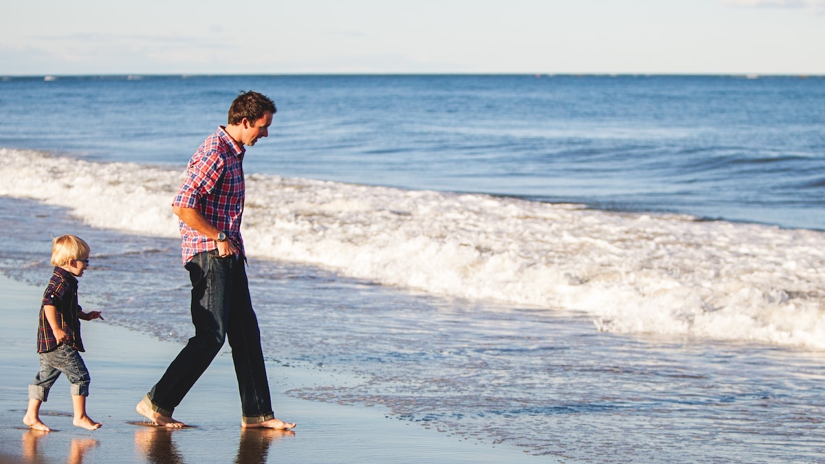 Father and toddler son walking in the waves at the beach