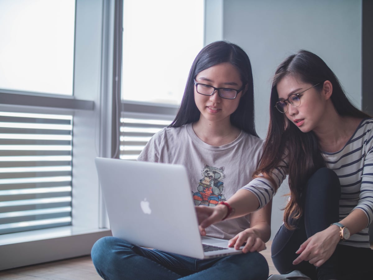 Two young women working on a laptop