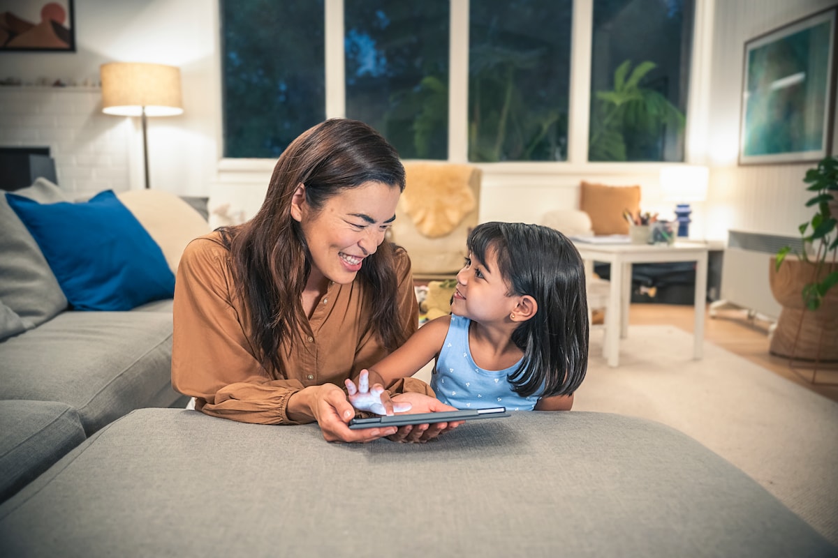 A woman and her child in a lounge room. They are looking at a tablet.