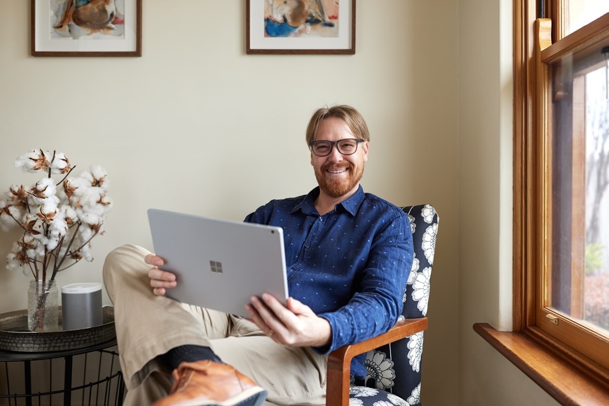 Adam, VPP customer sitting in an armchair with his tablet