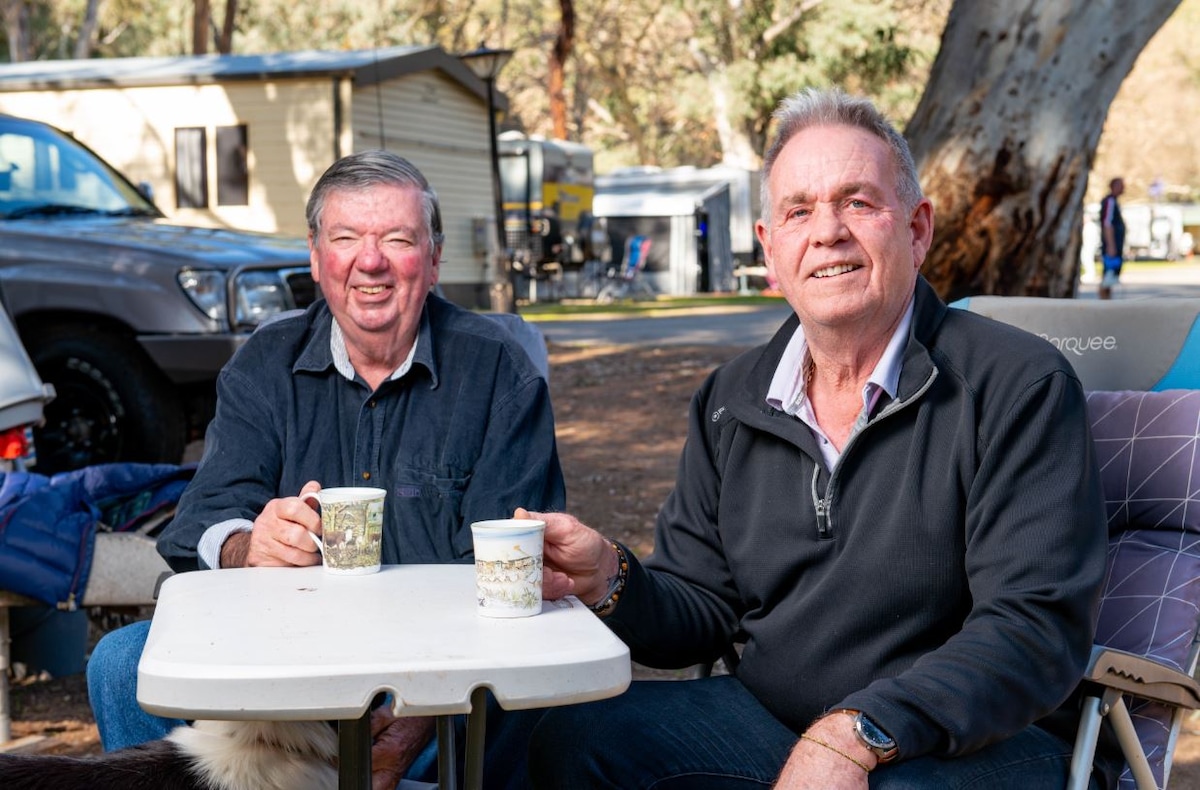 Two men sitting outside have a cuppa at caravan park