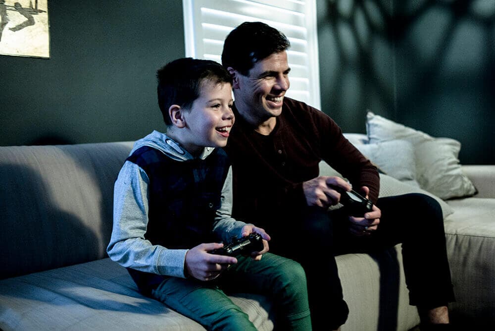 Father and son playing video games on the couch