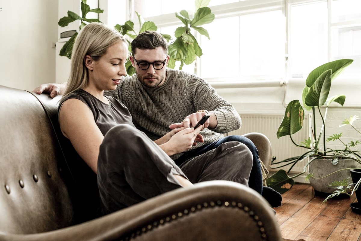 Couple sitting on lounge looking at mobile