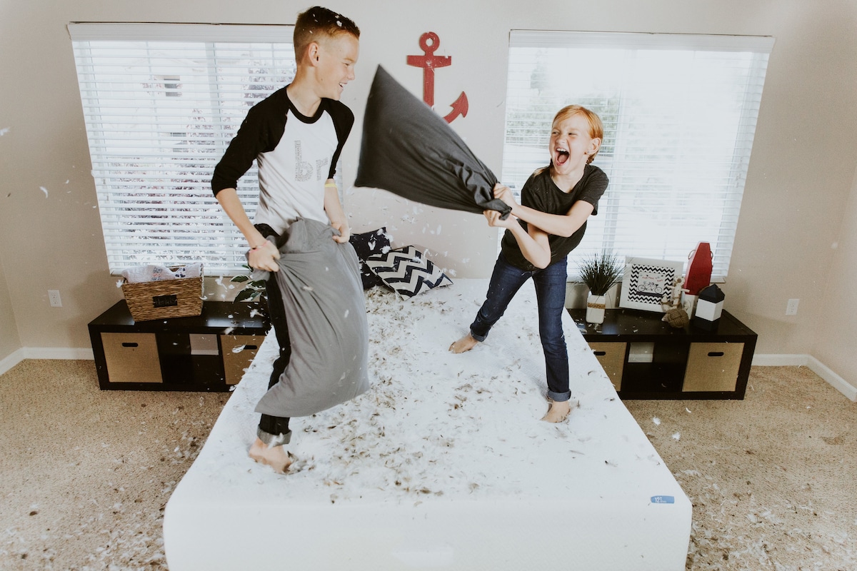 Two siblings having a pillow fight