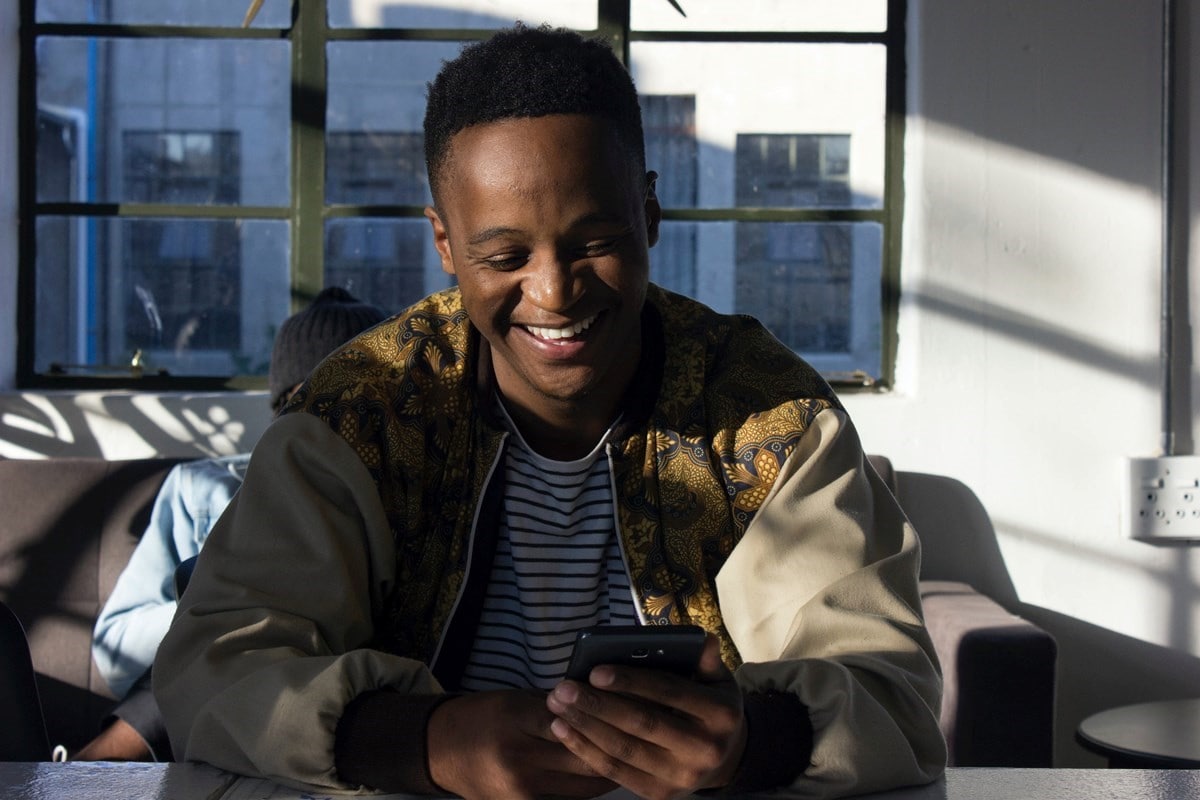 Young male smiling at his phone on the couch