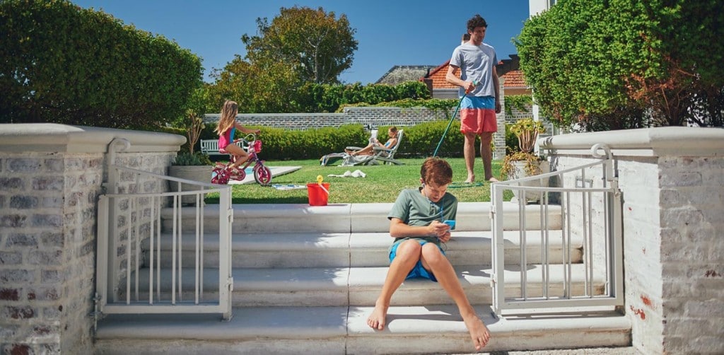 A family having fun in their backyard; lying by the pool, riding a bike and watering the garden