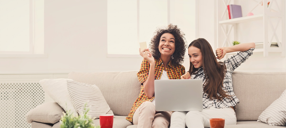 Two happy young women on a laptop