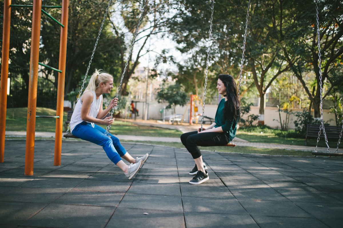 Two women wearing activewear enjoying a break on some swings