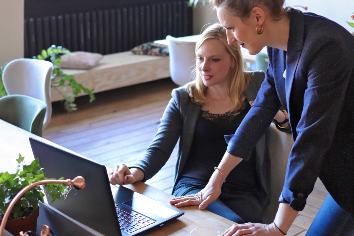 Two women discussing work at a laptop in the office.