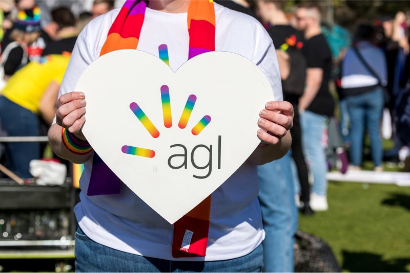 Employee holding up a heart shaped, rainbow AGL logo at Midsumma.