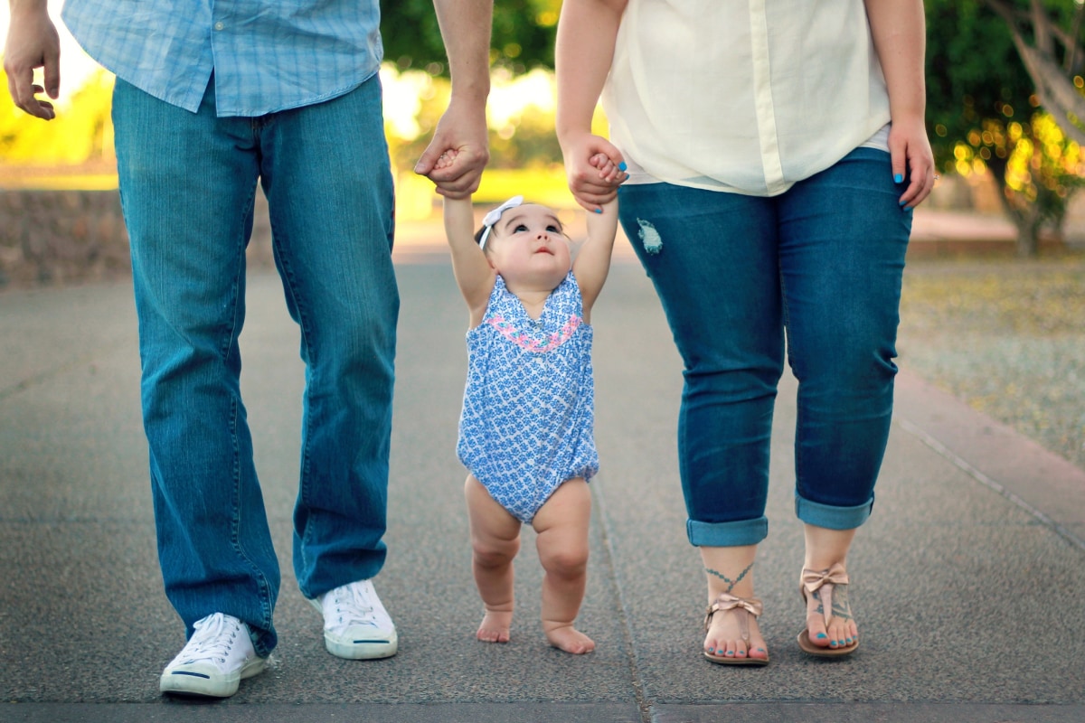 Parents helping to teach their baby to walk