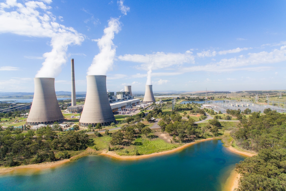 An aerial view of the Bayswater Power Station on a sunny day with cooling towers emitting steam.