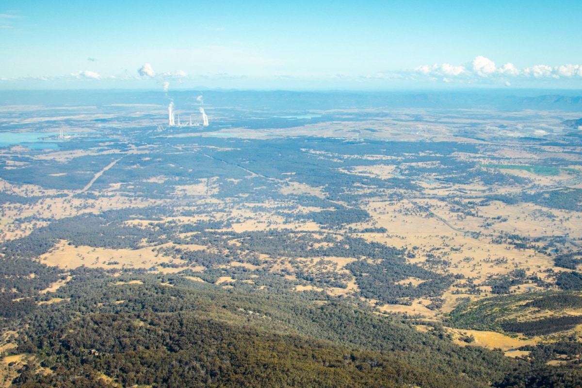 A long-distance aerial view of energy assets in the Hunter region, with cooling towers visible in the distance.