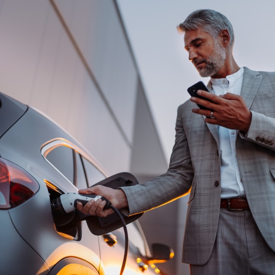 Man in grey business suit plugging in an electric vehicle to charge