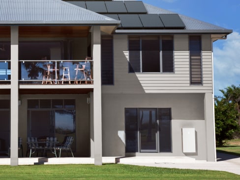 Two story house with a Tesla Powerwall 3 battery attached to the outside.