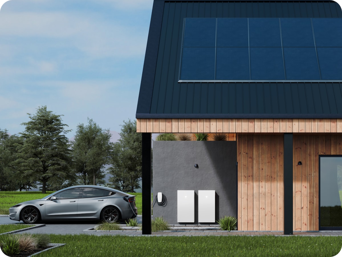 Image of a modern house displaying two Tesla powerwall batteries in the carport alongside an EV charger.  