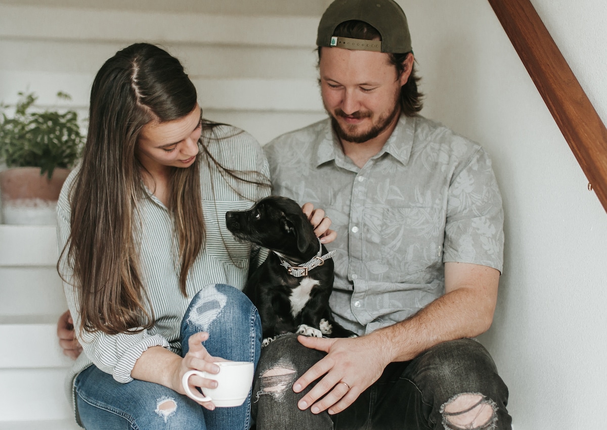 A couple petting their dog on some stairs.