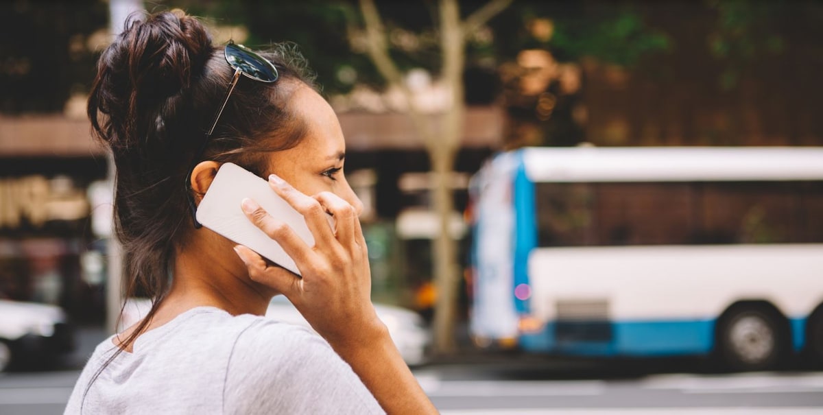 Young woman standing on sidewalk with mobile to ear