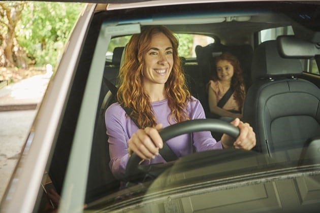 An electric vehile being driven by a women with her daughter in the backseat