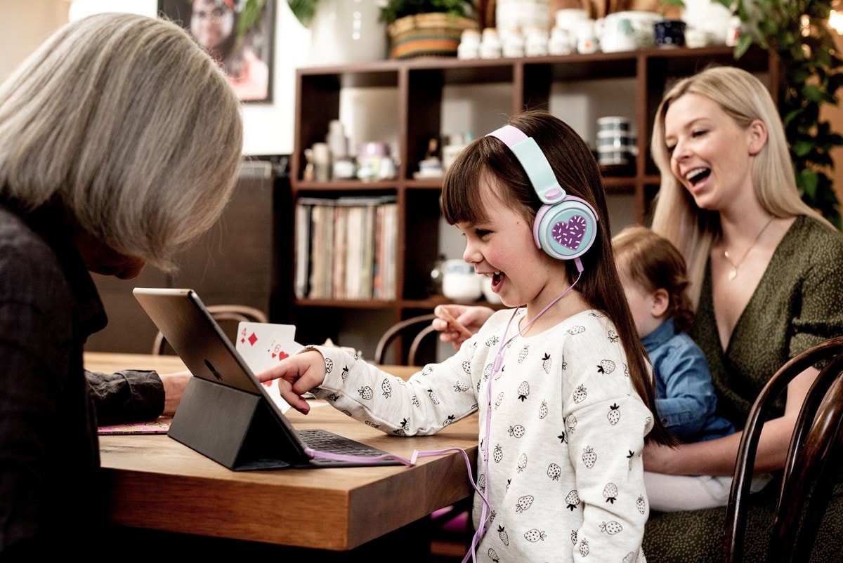 Family at dining table with girl in headphones and tablet 