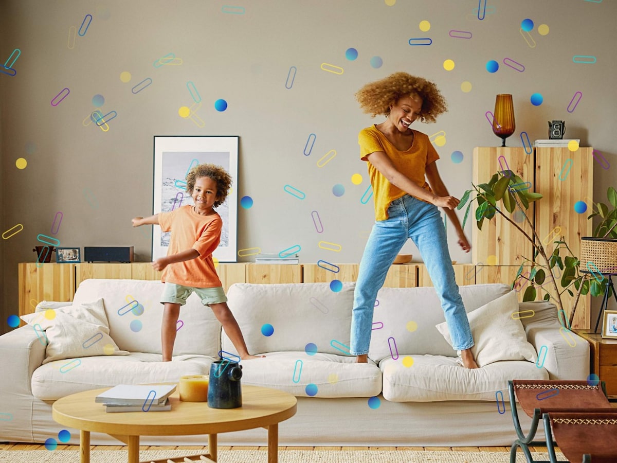 A child and adult jumping on a couch. Illustrated confetti shapes are superimposed on the image.